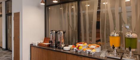 A breakfast bar with various food items, coffee makers, and juice dispensers.