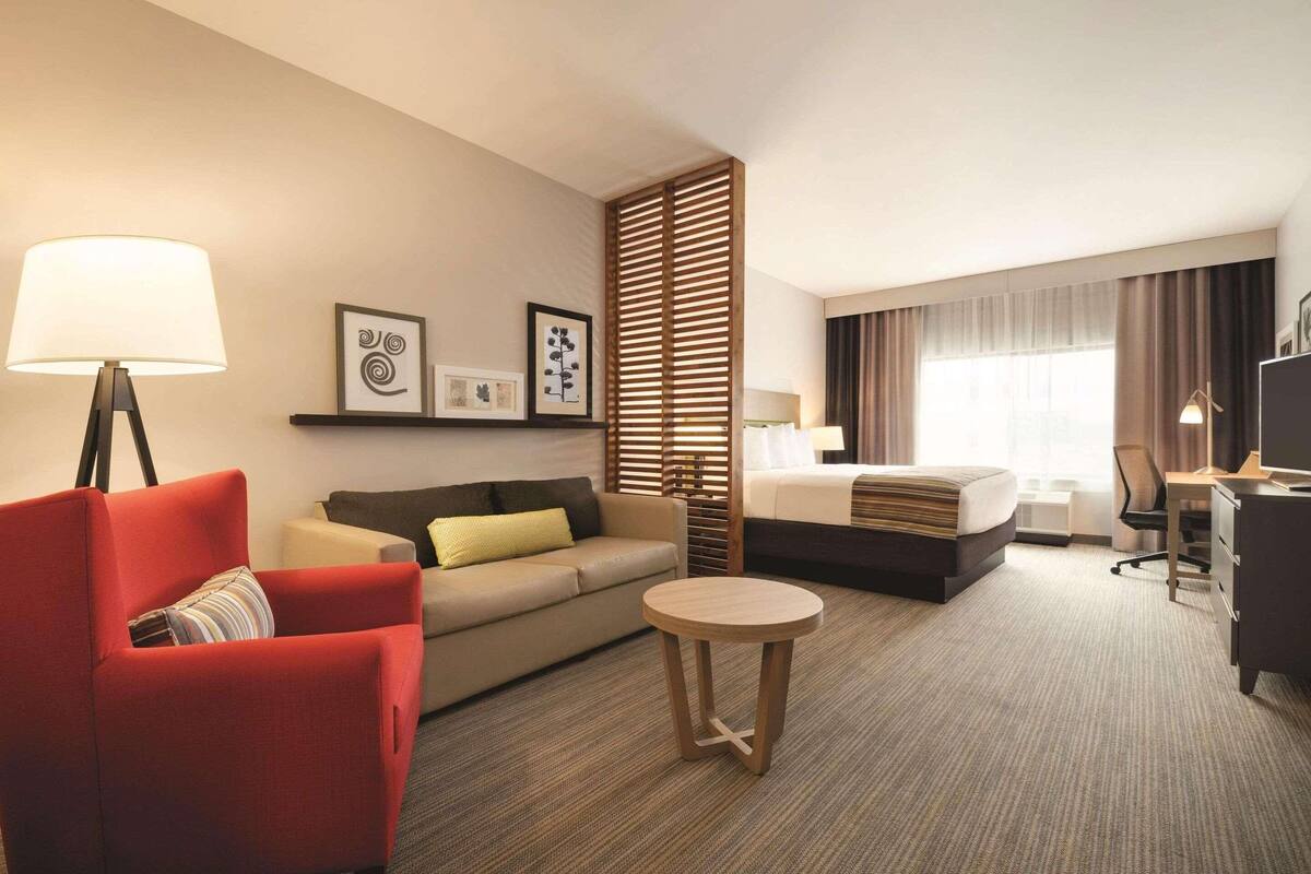 Ein Hotelzimmer mit einer Couch, einem runden Tisch, einem Bett, einem Schreibtisch und einem Fernseher.
