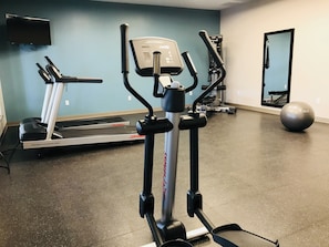 Ein Fitnessraum mit Laufband, Crosstrainer und stationärem Fahrrad.