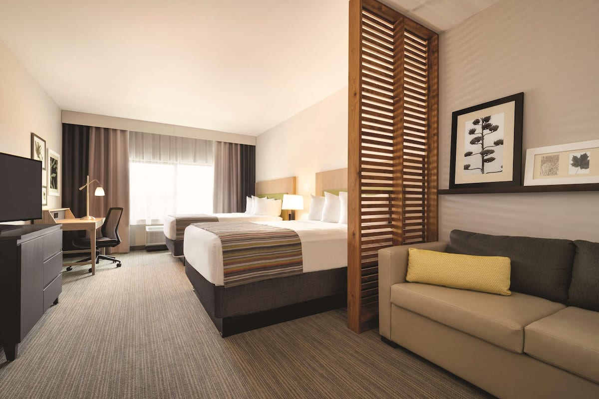 Ein Hotelzimmer mit Bett, Schreibtisch, Stuhl, Sofa und einem großen Fenster.