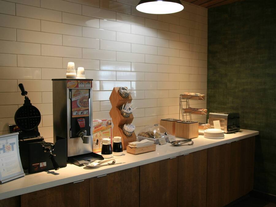Un bar à petit-déjeuner équipé d’un appareil à gaufres, d’une machine à café et de divers produits pour le petit-déjeuner.