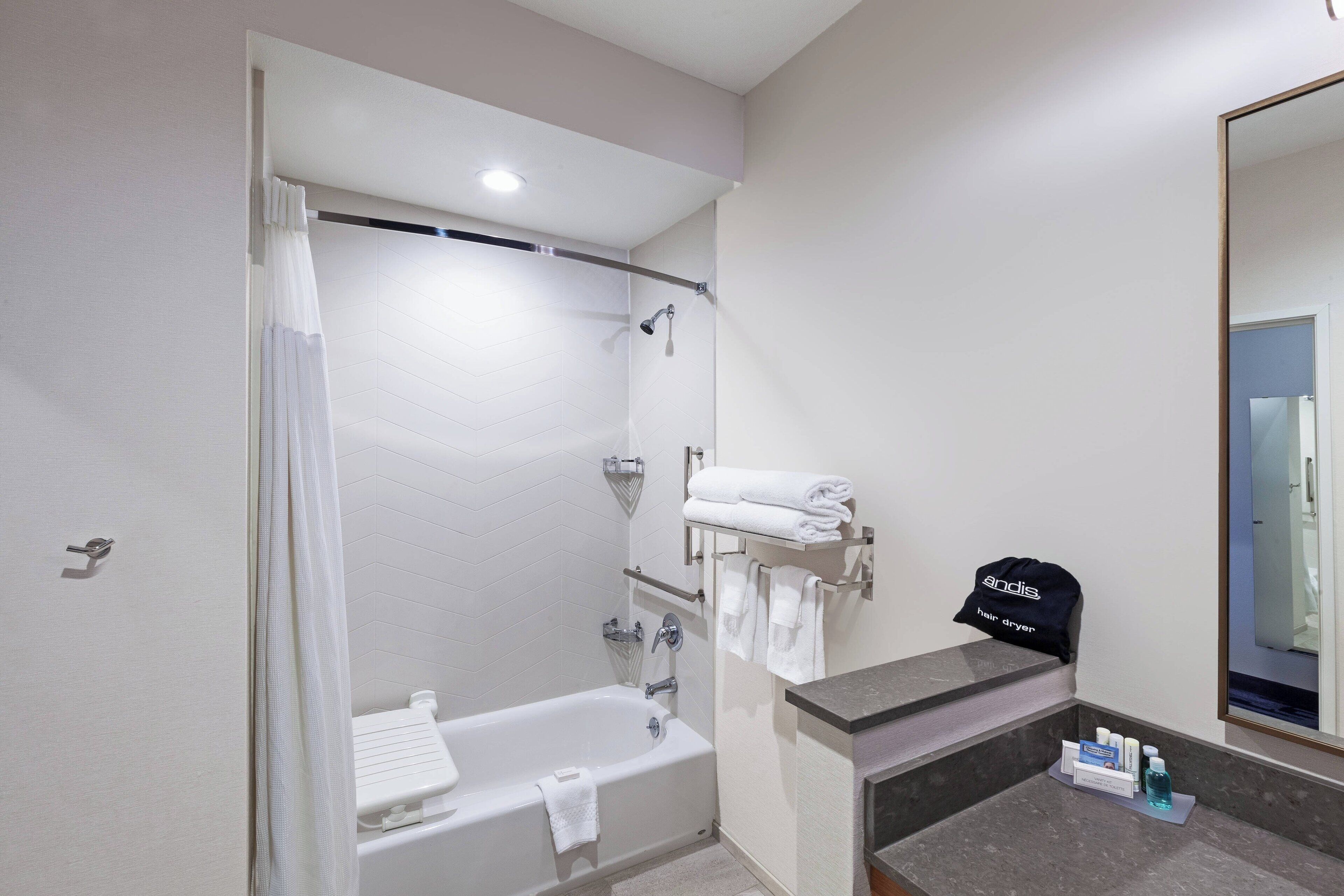 A modern bathroom with a shower, bathtub, and a vanity with a towel rack and a cap.