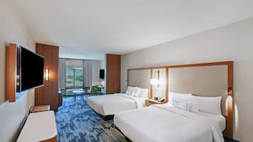 Une chambre d’hôtel avec deux lits, un téléviseur à écran plat, un bureau et une vue sur l’extérieur.