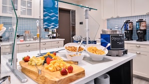 A buffet setup with various food items, including fruits and cereals, and a soup station.