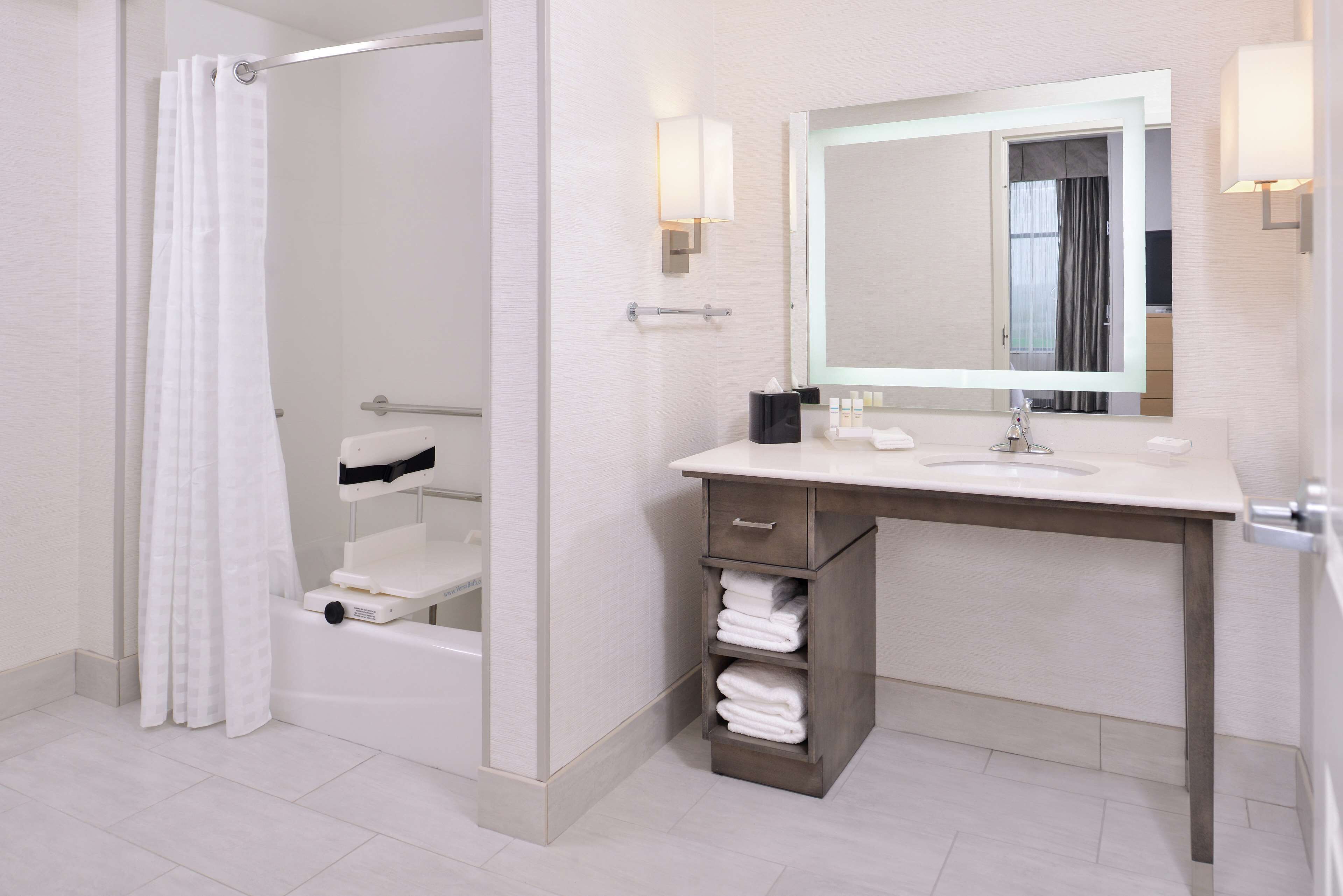 A modern bathroom with a shower, toilet, sink, and a mirror.