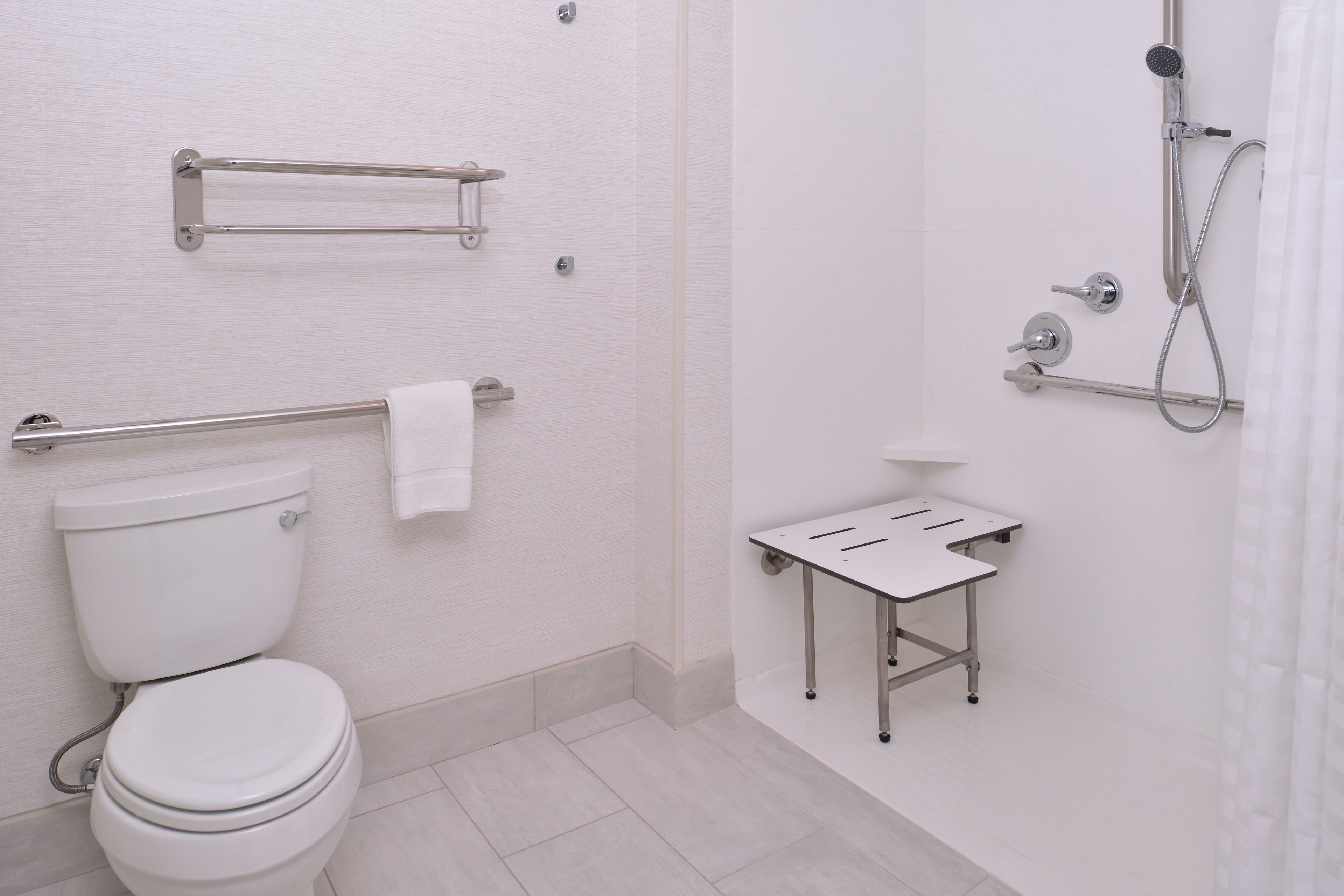 A modern bathroom with a toilet, a shower, and a small table with a towel.