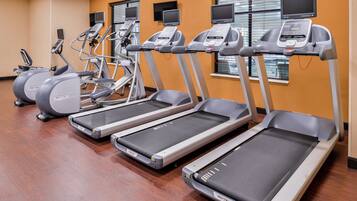 Un gimnasio con cintas de correr, elípticas y bicicletas estáticas.