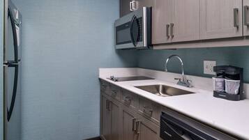 A compact kitchen with a refrigerator, microwave, sink, and dishwasher.