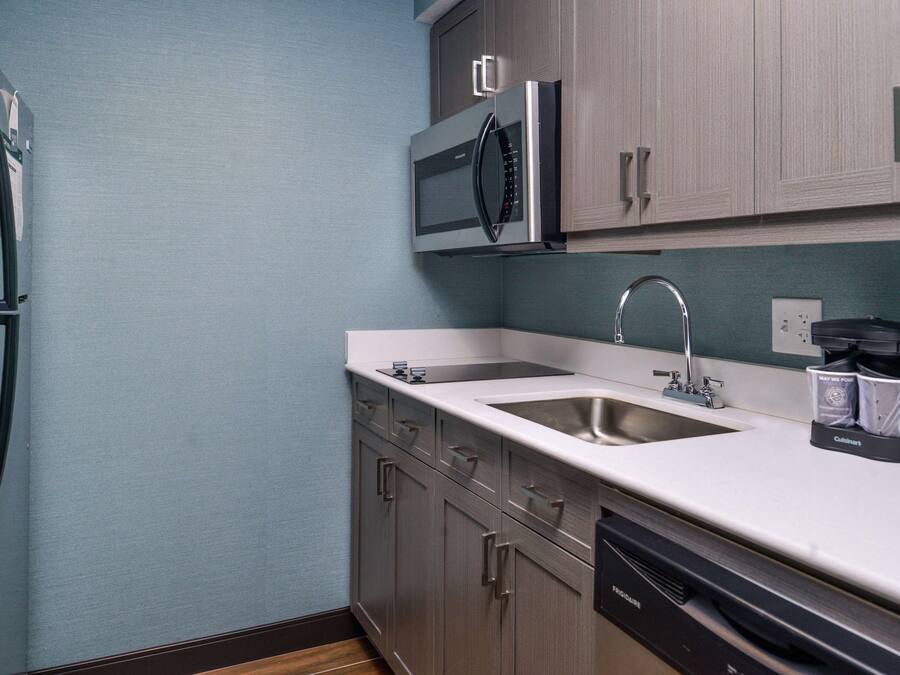A compact kitchen with a refrigerator, microwave, sink, and dishwasher.