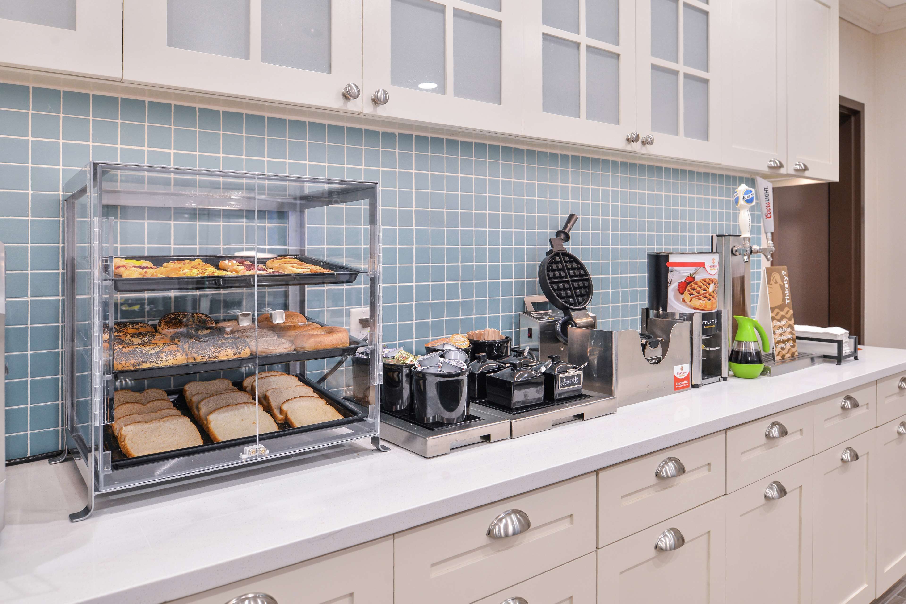 Een ontbijtbuffet met een pannenkoekenijzer, koffieapparaat en een broodpresentatie.
