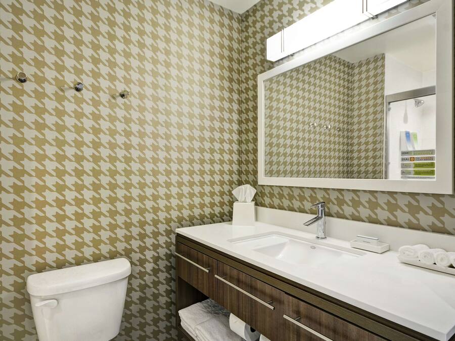 Un baño con lavamanos blanco, espejo y retrete.