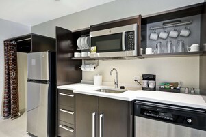 Una cocina moderna con electrodomésticos de acero inoxidable, lavavajillas integrado y cafetera.