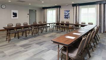 Un salón de conferencias con una larga mesa, varias sillas, un reloj y una puerta.