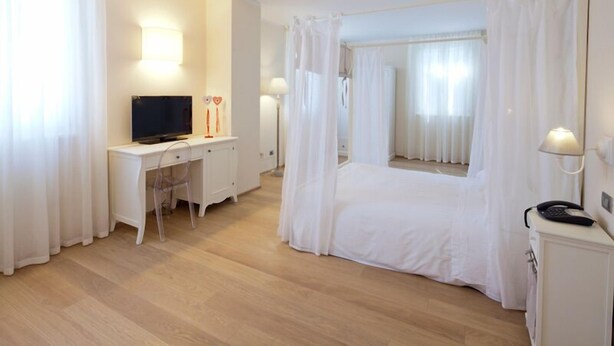 A hotel room with a bed, a desk, a chair, a television, and a telephone. - Villa Pepoli (Occhiobello)