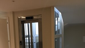 A modern elevator with glass doors, a wooden floor, and a light fixture on the ceiling. - Villa Pepoli (Occhiobello)