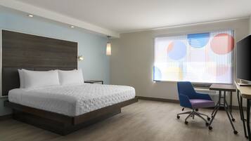 Een moderne hotelkamer met een groot bed, een bureau en een stoel.