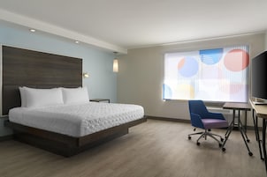 Una habitación de hotel moderna con una cama grande, un escritorio y una silla.