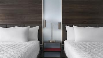 Una habitación de hotel con dos camas, una mesita de noche y una lámpara moderna.