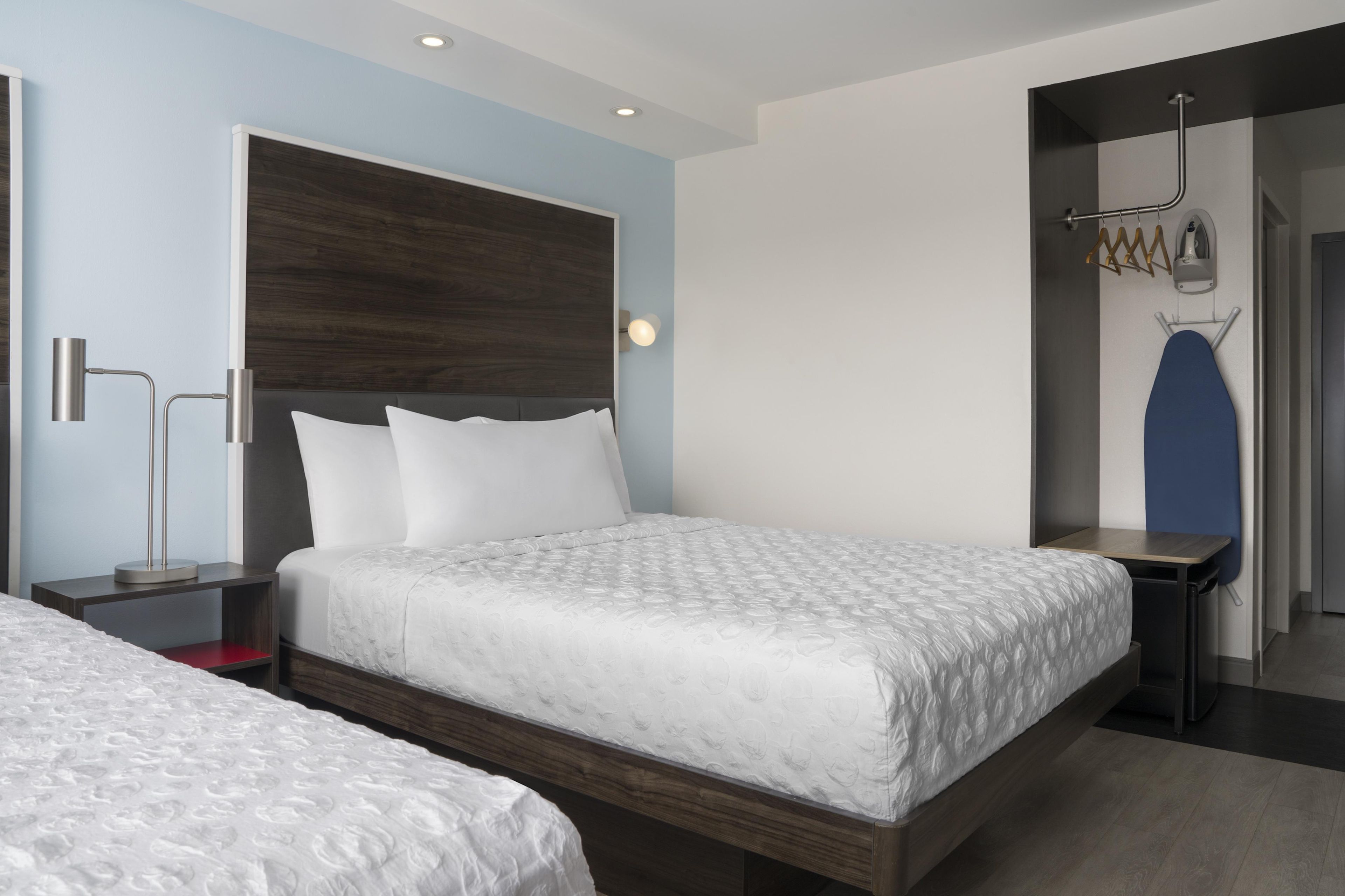 A modern hotel room with a large bed, bedside tables, a wardrobe, and a mirror.