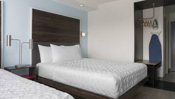 A modern hotel room with a large bed, bedside tables, a wardrobe, and a mirror.
