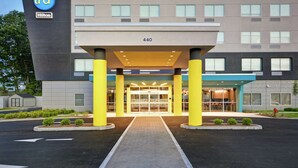 A modern hotel entrance with a glass door, a visible address number, and a clear pathway leading to the entrance. - Tru by Hilton Chicopee Springfield (Chicopee)