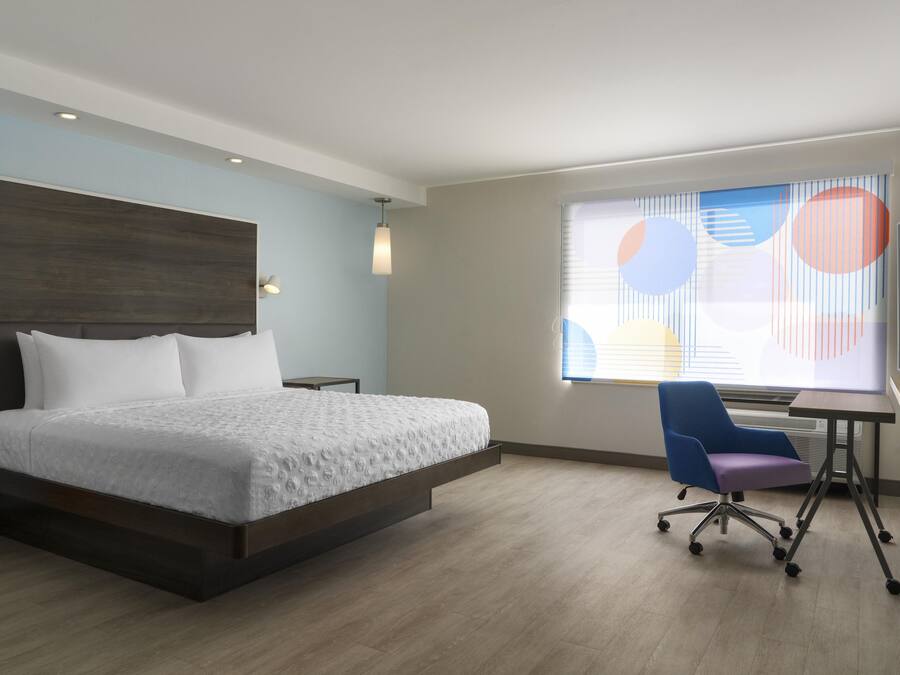 Una habitación de hotel moderna con una cama grande, un escritorio y una silla.