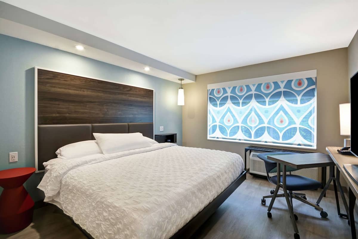 Habitación de hotel moderna con una cama grande, un escritorio y vistas a una ventana con diseño.