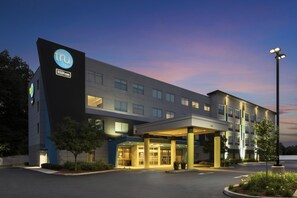 A modern hotel building with a prominent 'tru' logo, multiple floors, and a covered entrance area. - Tru by Hilton Chicopee Springfield (Chicopee)