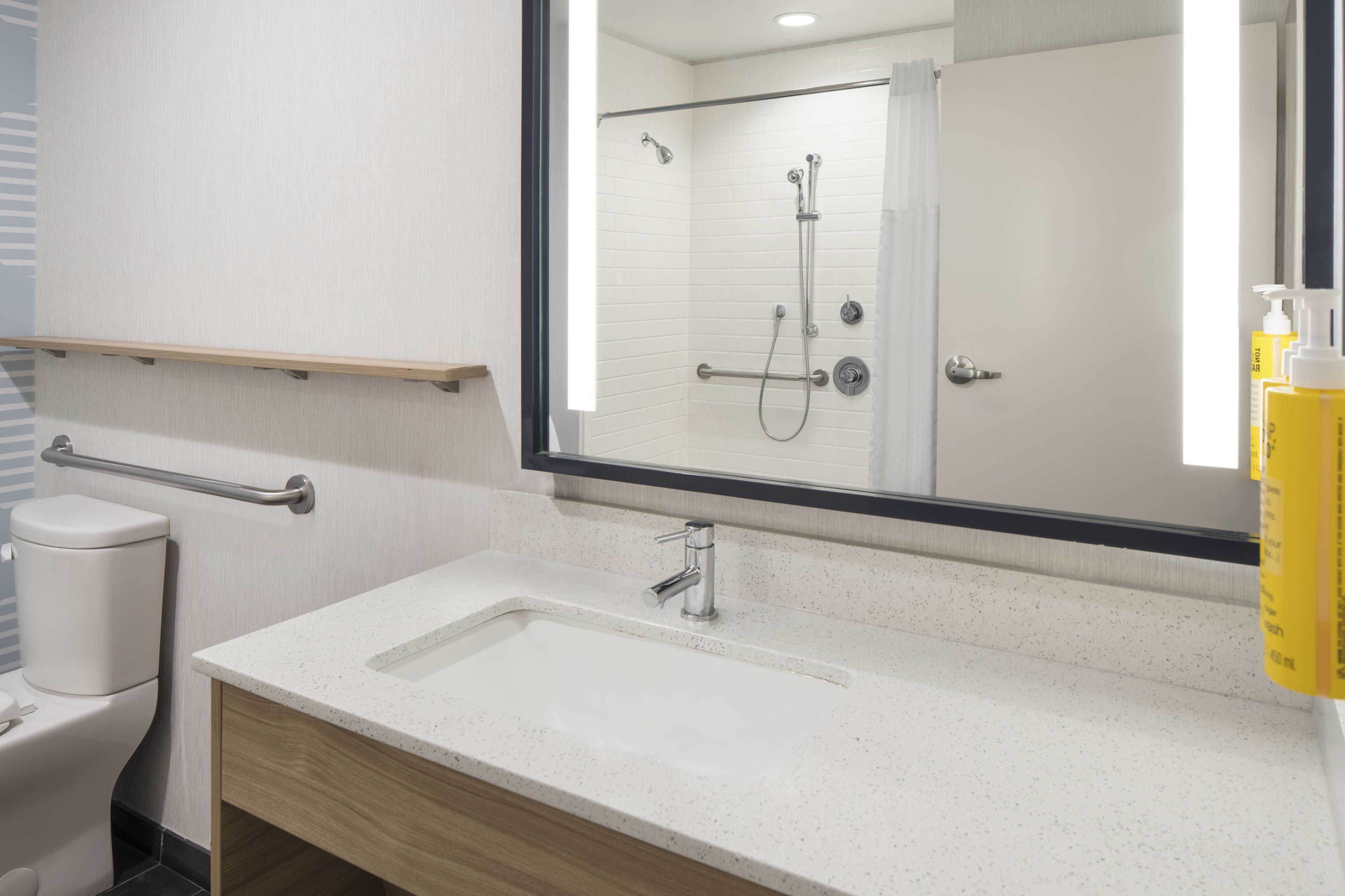 A modern bathroom with a white sink, a mirror, and a shower.