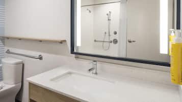 A modern bathroom with a white sink, a mirror, and a shower.