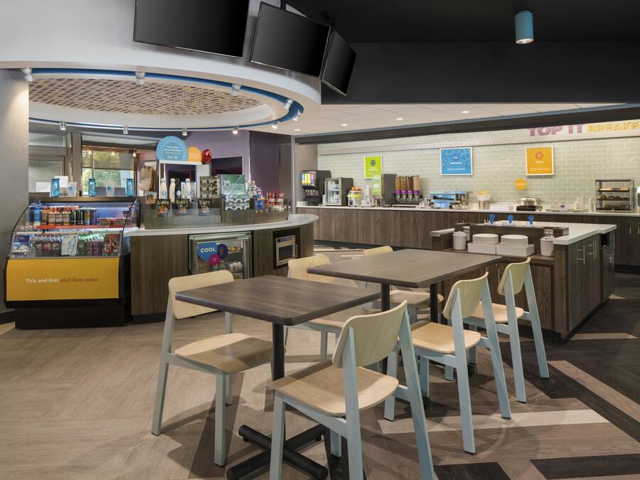 Espaço de café da manhã moderno com assentos, cafeteira e diversas opções de comida.
