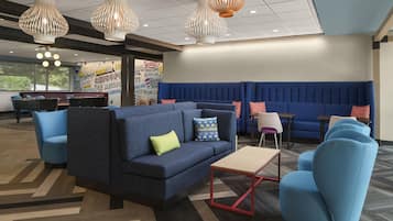 A modern lounge area with blue seating, a coffee table, and decorative lighting.