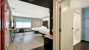 A modern hotel room with a bed, desk, and chair, a small kitchenette, and a bathroom with a shower and toilet. - Tru by Hilton Chicopee Springfield (Chicopee)