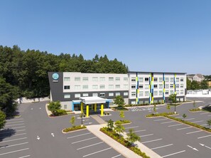 A modern hotel building with a parking lot and a green landscape. - Tru by Hilton Chicopee Springfield (Chicopee)