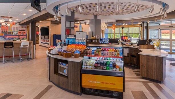 Una cafetería moderna con un mostrador central, zona de estar y una exhibición de bebidas.