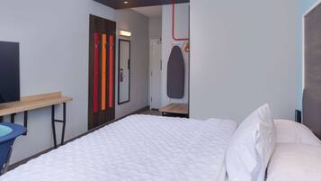 Una habitación de hotel moderna con una cama grande, un escritorio y un espejo.