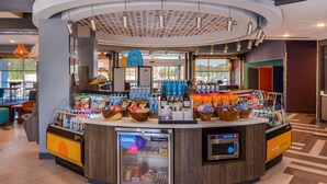 Un quiosco moderno de autoservicio con una sección refrigerada, diferentes snacks y agua embotellada.