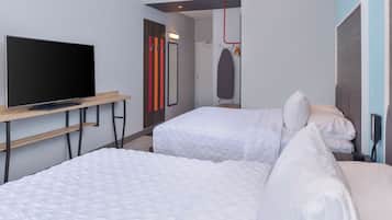 Een hotelkamer met twee bedden, een tv op een standaard, een kledingkast en een spiegel.