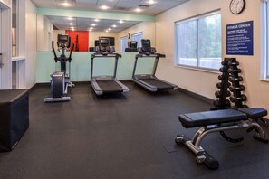 Une salle de sport équipée de tapis de course, d’un appareil elliptique et d’un banc de musculation.