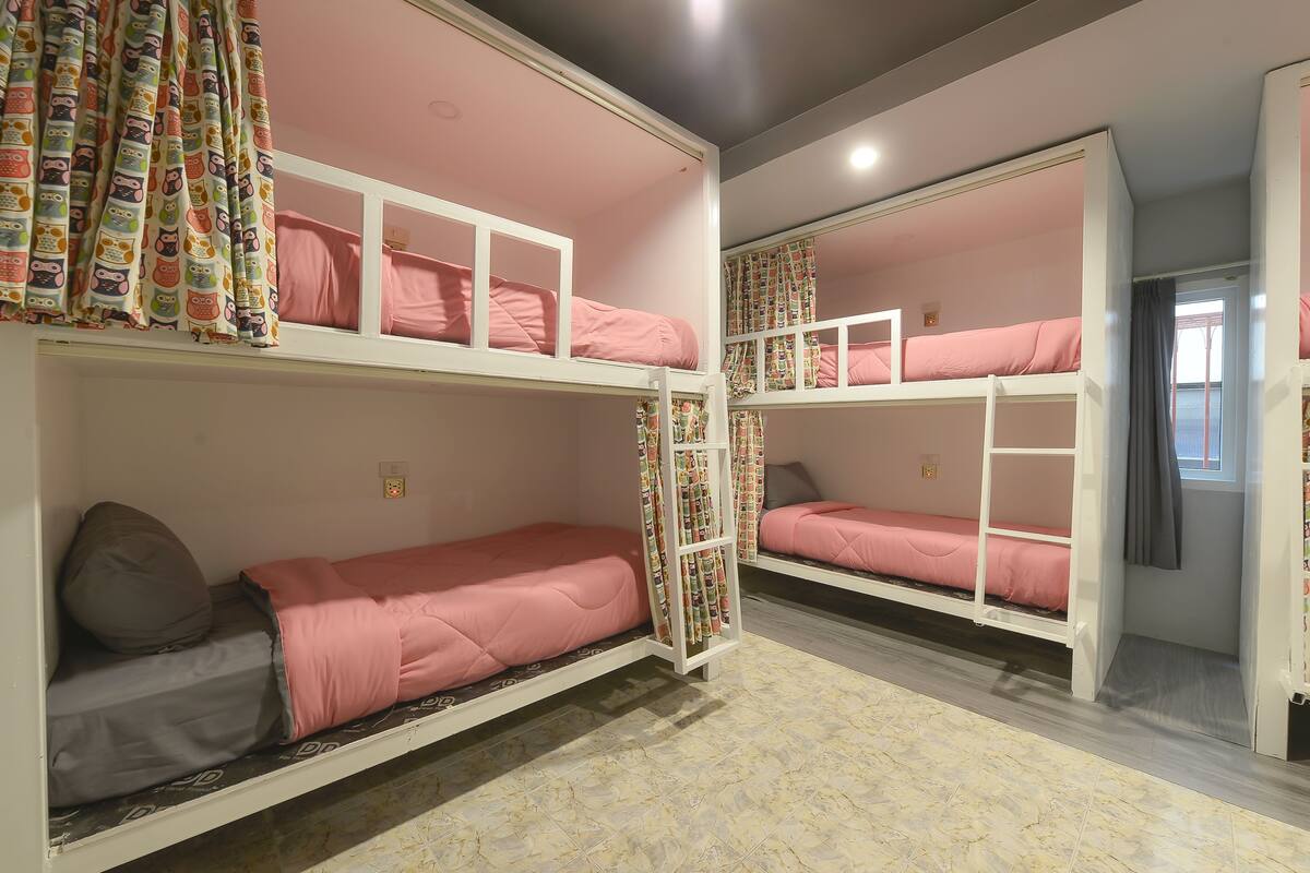 A bunk bed room with pink bedding and patterned curtains.