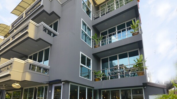 Um edifício moderno de vários andares com piscina, janelas amplas e área de estar externa.