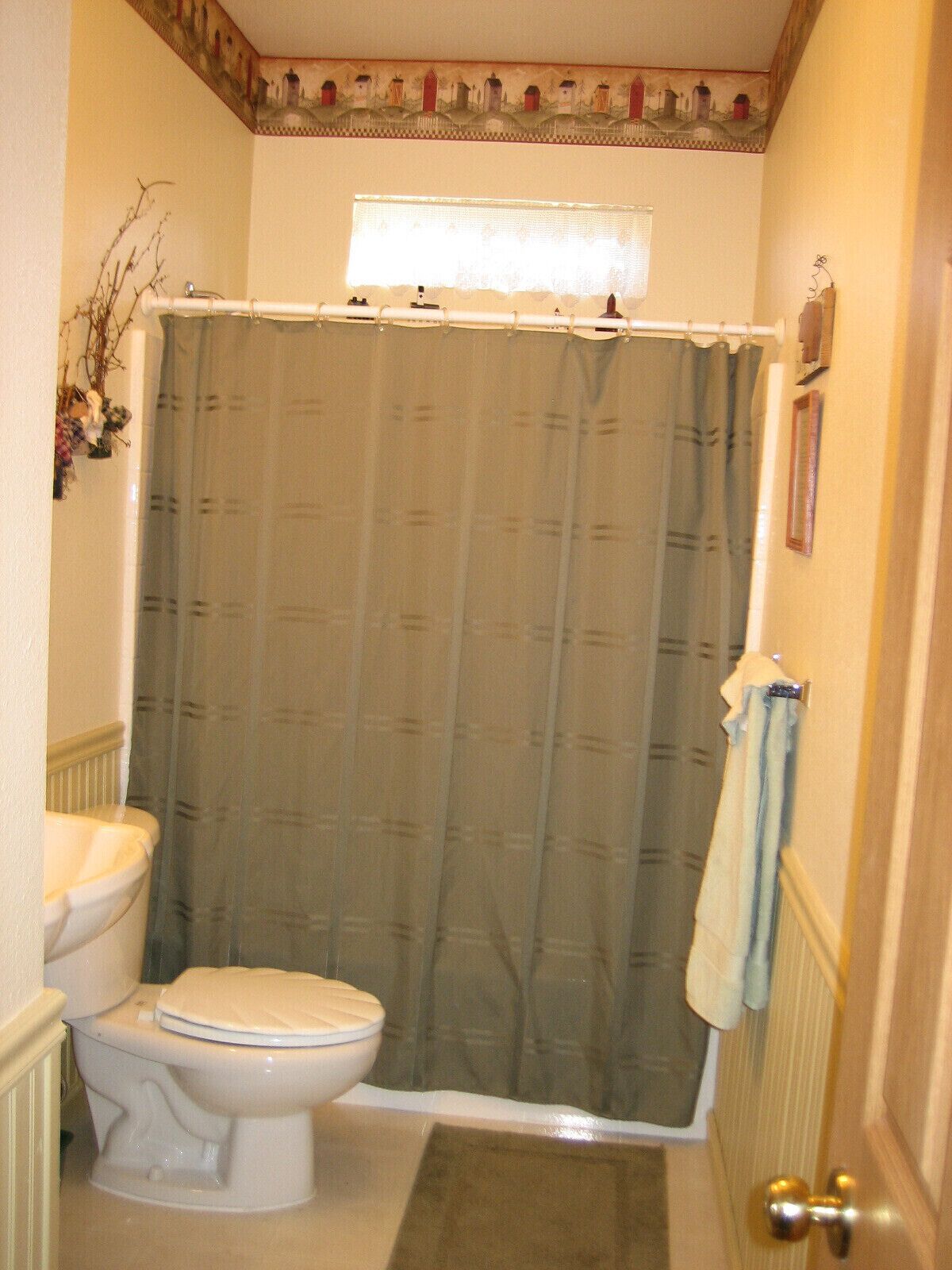 Une salle de bain avec des toilettes, un rideau de douche et une serviette accrochée au mur.