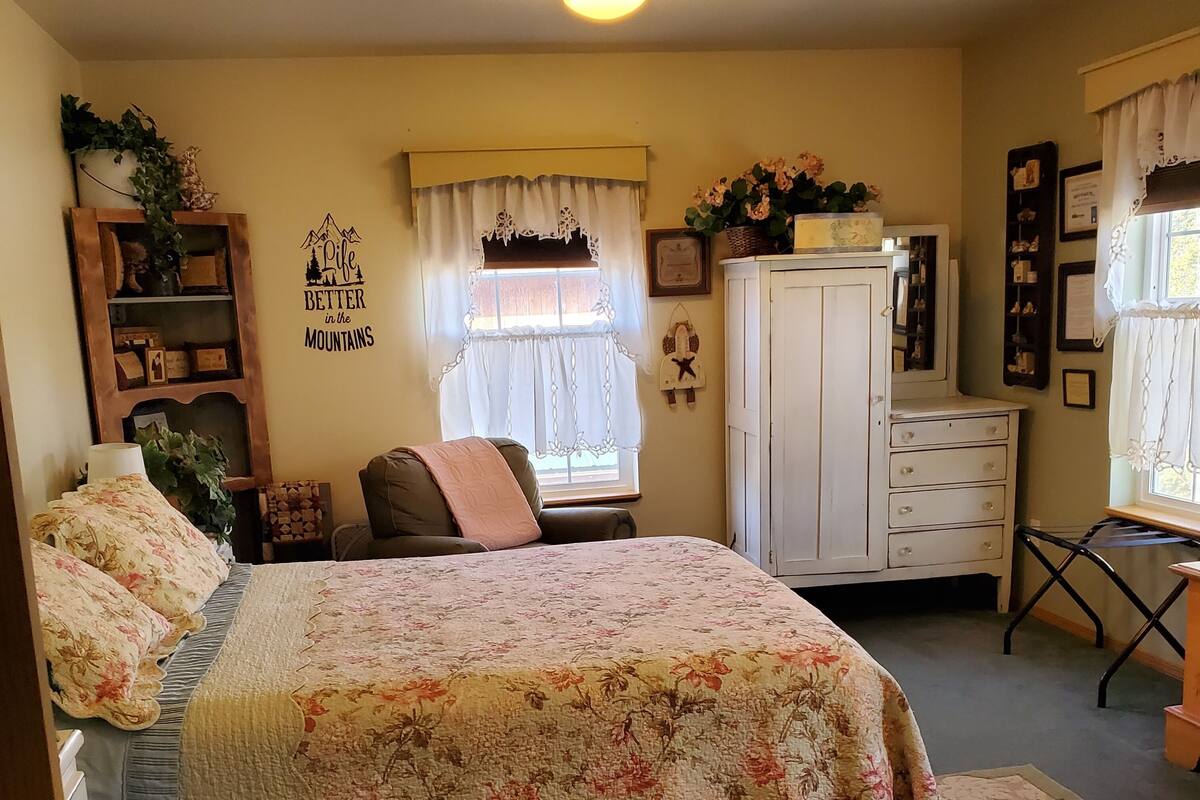 A bedroom with a bed, a dresser, a chair, and a window with curtains.