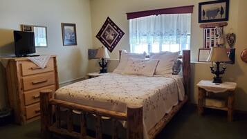 A bedroom with a wooden bed, a dresser, a television on top, and a window with curtains.