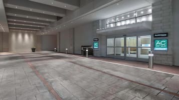 A spacious lobby with a modern design, featuring a reception desk, a coffee machine, and signage for AC Hotels and Marriott.