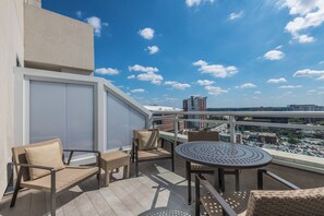 A balcony with wicker furniture, a round table, and a view of the cityscape. - AC Hotels by Marriott Charlotte City Center (Charlotte)
