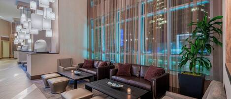 A modern lobby with leather sofas, a reception desk, and a large window with city lights.