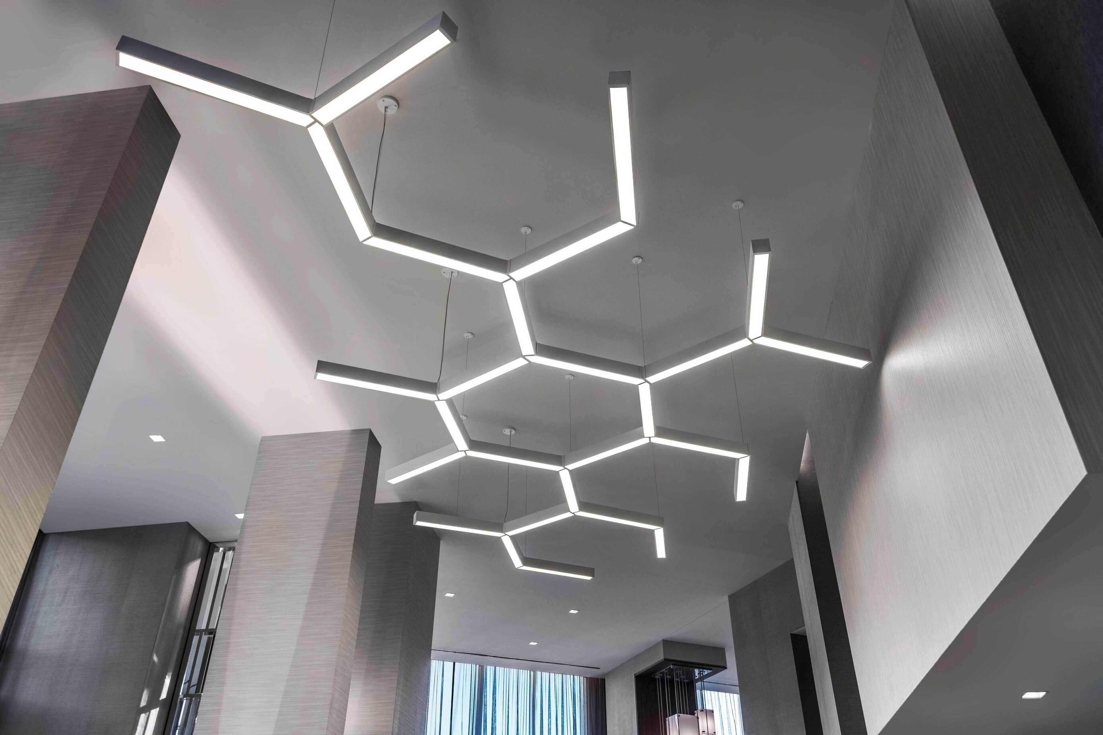A modern interior with geometric ceiling lighting and large windows.