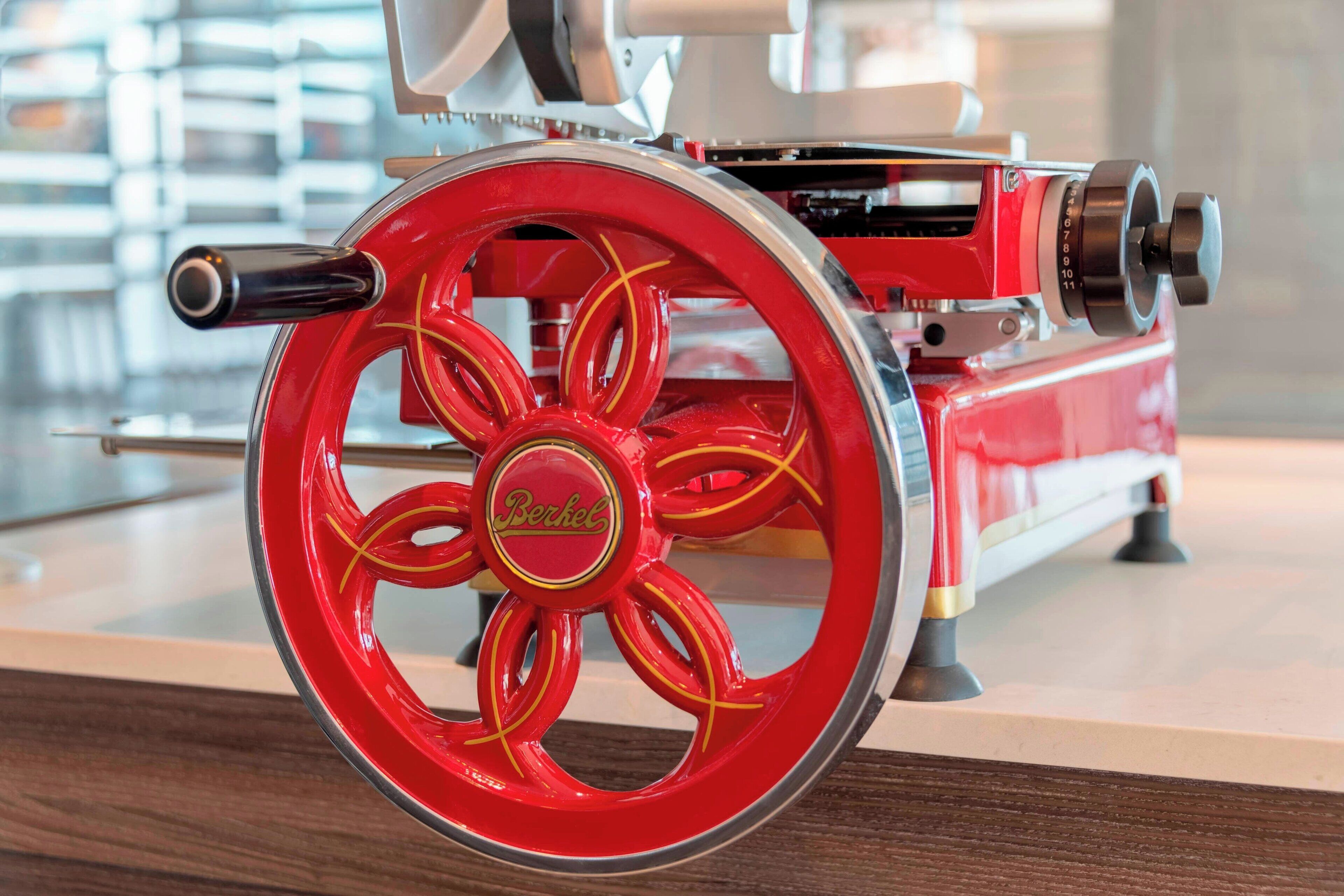 A red and gold vintage machine with a prominent wheel and the word "Berkel" on it.