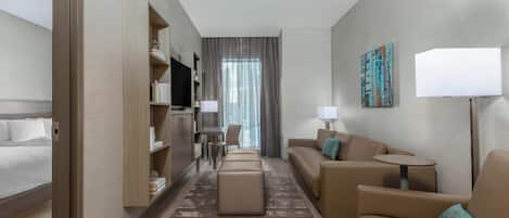 Une chambre d’hôtel moderne équipée d’un lit, d’un canapé, d’une petite table, d’une télévision et d’un bureau avec une chaise.